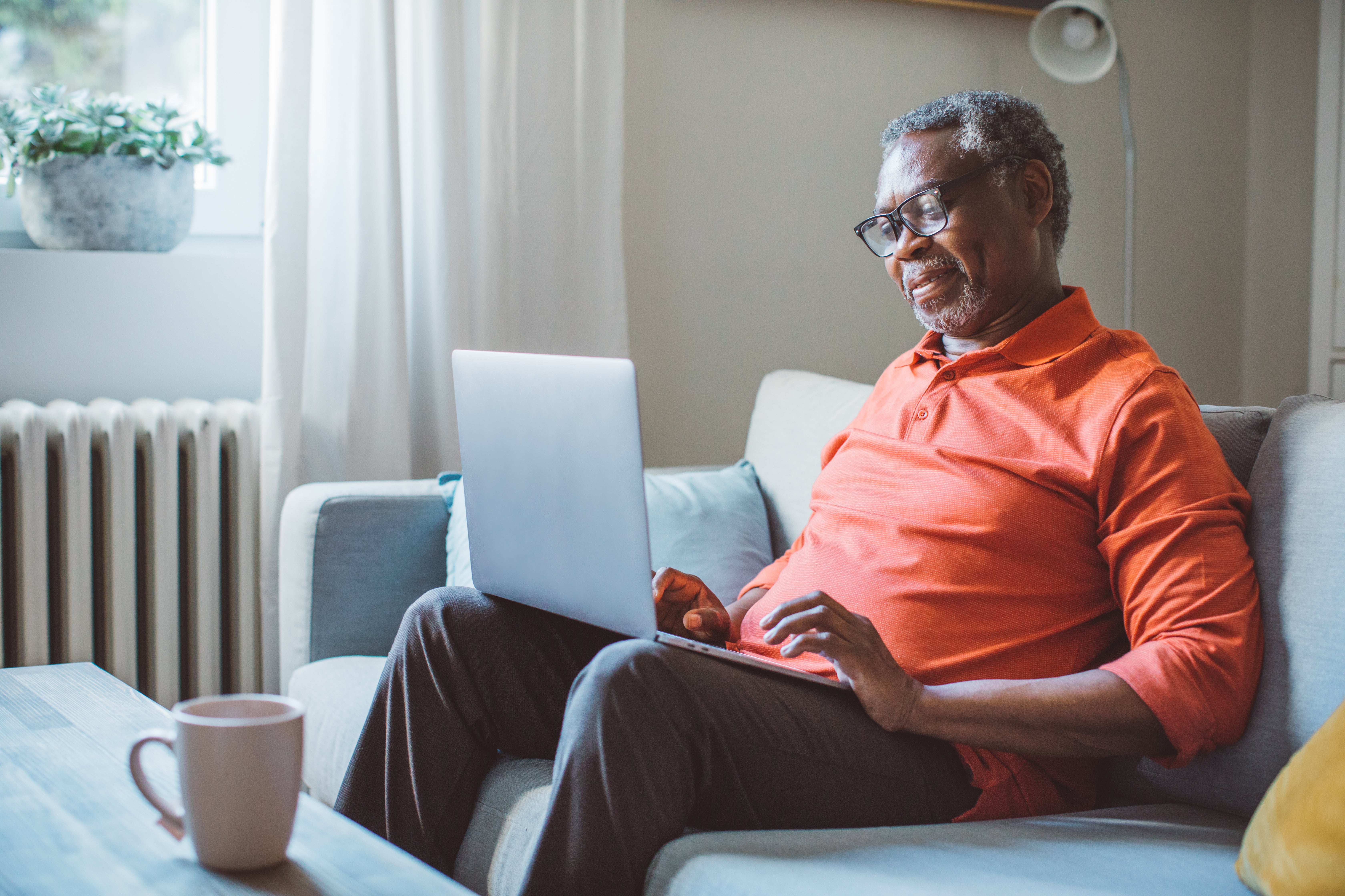 An older man uses a laptop computer at home