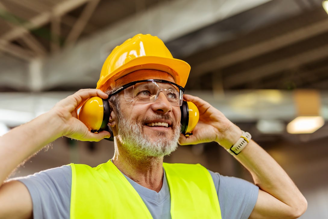 A construction worker puts on headphones to protect his hearing